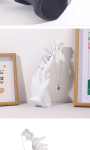 Close-up of white resin hand jewelry holder with a carved rose for ring and necklace display