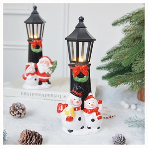 Detail of Christmas lantern decoration featuring snowman and Santa figures on snowy table