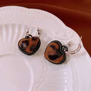 Retro heart-shaped leopard print earrings with silver hooks on white relief plate