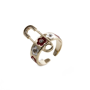 Détail d'une bague épingle à nourrice dorée avec fleurs en émail et détails en zircon