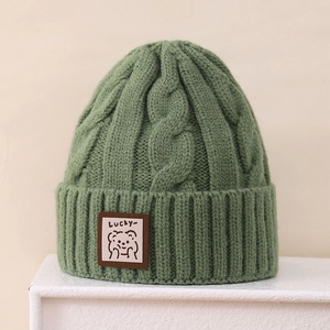 Close-up of grass green cable knit beanie featuring a cute Lucky bear patch detail