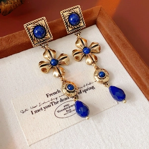 Detail of vintage gold-tone earrings with dark blue teardrop stones and floral accents