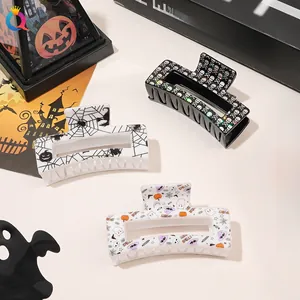 Three Halloween claw clips with skull, spider web and ghost prints on a beige desk