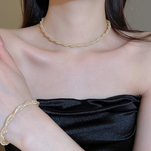 Close-up of golden mesh twist necklace and bracelet set worn on skin with shimmering glow