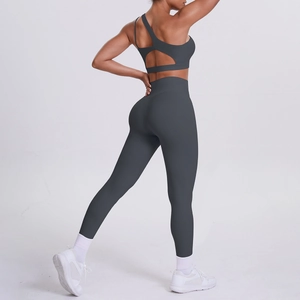 Detail view of dark grey one-shoulder sports bra and high-waisted yoga leggings
