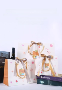 Detailed view of three cartoon bear gift bags with woven handles and satin ribbons