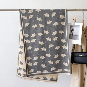 Detail of soft cashmere-feel scarf with ginkgo leaf pattern hanging on a rack