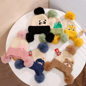 Flat lay of six colorful winter knit hats with faux fur pompoms and cartoon animal patches