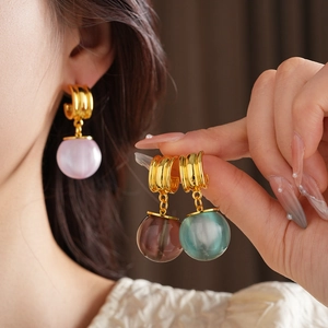 Detail view of translucent resin pendant earrings in lavender and green with golden metal