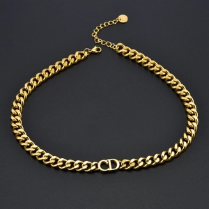 Macro detail of gold Cuban chain necklace with CD letter charm on black background