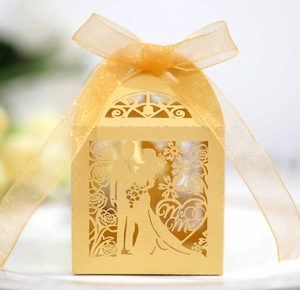 Detail of laser-cut gold wedding favor box with Mr & Mrs text and ribbon bow
