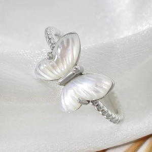 Macro shot of silver butterfly ring with mother of pearl wings on silk fabric