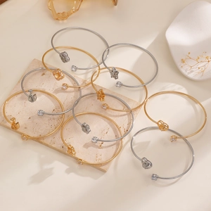Détails de bracelets dorés et argentés avec breloques trèfle et étoile sur pierre