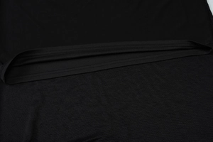 Gros plan de l'ourlet de robe noire avec coutures de précision et maille texturée