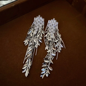 Macro shot of silver wheat leaf fringe earrings with zircon on a velvet jewelry box