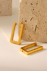 Macro detail of rectangle gold earrings on stone base with high polish finish