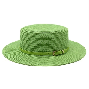 Détail d'un chapeau de paille vert vif avec fine ceinture et boucle dorée