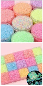 Close-up of assorted luminous glass seed beads in colorful jars and organizer boxes