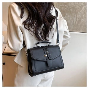 Detail of black PU leather crossbody bag with silver buckle and adjustable strap