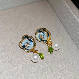 Detail of French enamel flower earrings with pearls and crystals in a velvet jewelry box