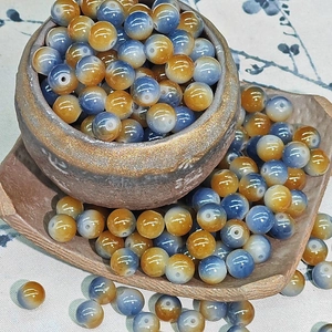 Macro shot of 8mm orange and blue gradient glass beads in a ceramic bowl for DIY jewelry