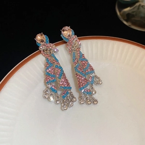 Detail of pink crystal tassel earrings with blue rhinestone fringes on a white ceramic plate