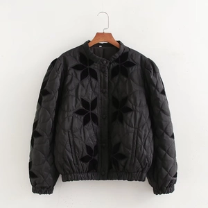Women's black quilted jacket with floral appliques and glossy finish on wooden hanger