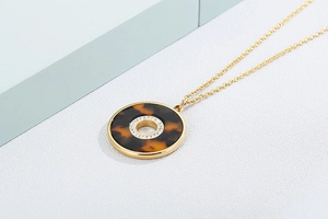 Macro detail of gold necklace with leopard print pendant and rhinestone circle