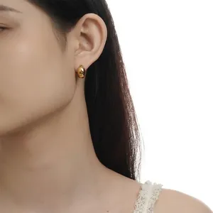 Detail of minimalist gold bean-shaped earrings on model with high-gloss finish