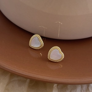Close-up of heart-shaped gold studs with iridescent shell inlay and twisted metal border