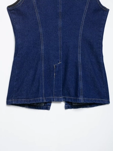 Detail of dark blue denim vest back featuring classic yellow double stitching craftsmanship