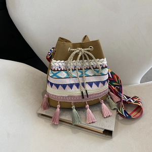 Detail of ethnic embroidery and colorful tassels on a khaki canvas bucket bag