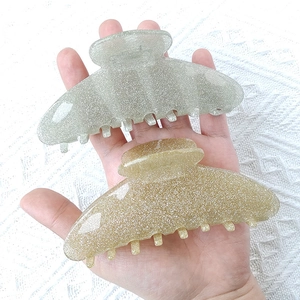 Glitter acrylic shark hair clips in green and gold colors shown in hand display