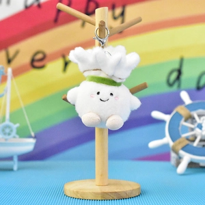 Cute cartoon shuttlecock plush keychain hanging on a wooden display stand for bags.
