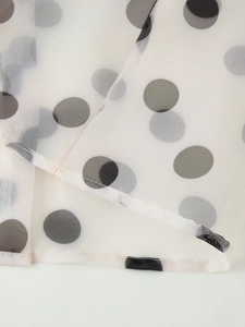Detailed view of white semi-transparent organza fabric with classic black polka dots
