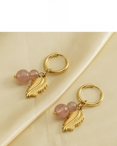 Detail of 18k gold plated feather earrings with natural pink stone on silk background