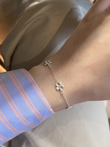 Detail of a minimalist s925 silver flower bracelet worn on a female wrist for fashion