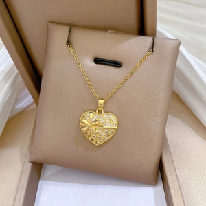 Gros plan d'un collier pendentif cœur doré avec nœud et cristaux pavés sur soie
