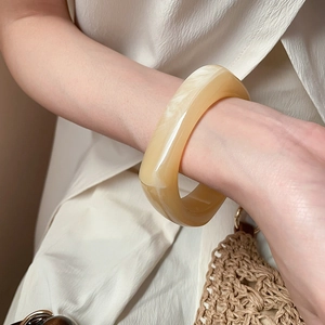 Close-up of cream acrylic marble bangle on woman's wrist with minimalist styling