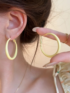Close-up of a large cream yellow hoop earring with matte finish worn by a model