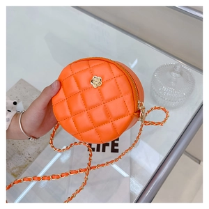 Close-up of orange quilted circle bag with a golden camellia buckle and chain strap