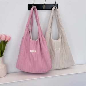 Detailed view of pink and beige pleated fabric tote bags showing brand woven label