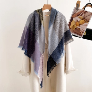 Detail of colorful plaid scarf with soft fringe, draped over a beige winter coat
