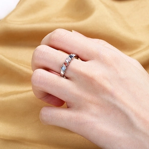 Minimalist silver ring with four colorful zircon stones worn on model hand with gold silk