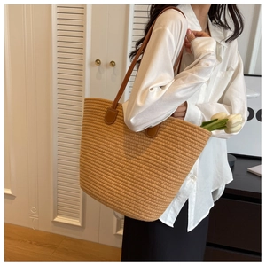 Detail of handwoven khaki tote bag with premium brown leather straps on a model