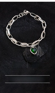 Detail of silver-plated copper chain with green zircon heart and cross charms