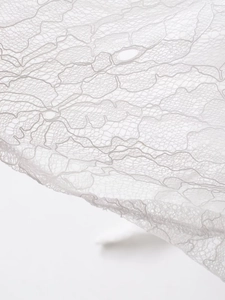 Macro detail of white floral lace mesh fabric with intricate mesh texture and fibers