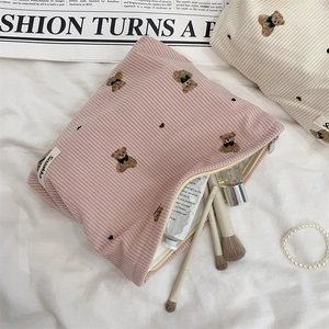 Close-up of corduroy makeup bags with bear embroidery and cosmetics inside