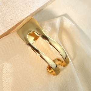 Polished gold-plated irregular wavy open cuff bangle bracelet for women on silk background