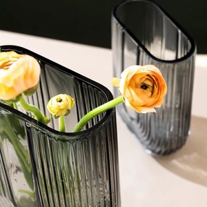 Nordic U-shaped gray glass vase with vertical stripes and yellow flowers in living room